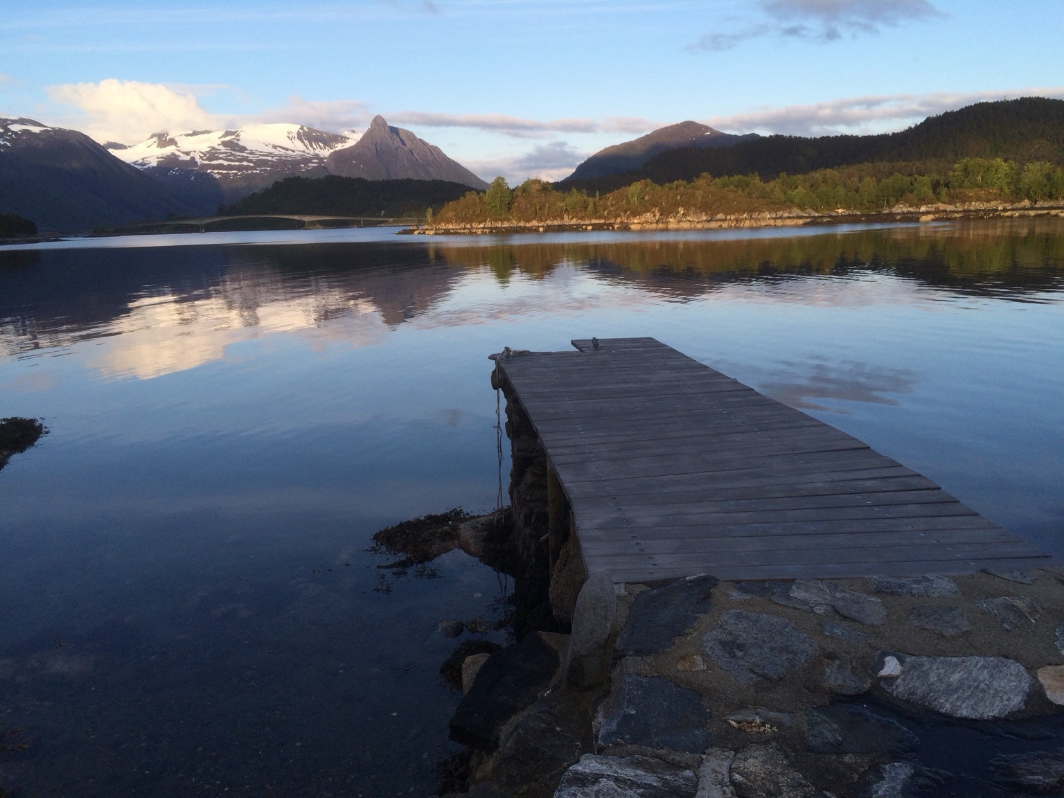 Brygge ved stille vann med fjell i bakgrunnen. Foto fra Torbjørn Skeides eget bildearkiv.